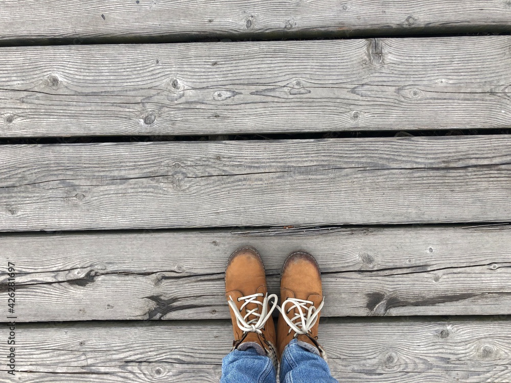 Background feet on a wooden sidewalk, abstraction, boots on a wooden walkway Background feet on a wooden sidewalk, abstraction, boots on a wooden walkway