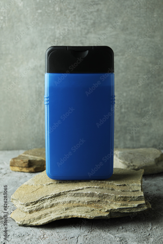 Bottle of shower gel on stone on gray textured table Bottle of shower gel on stone on gray textured table