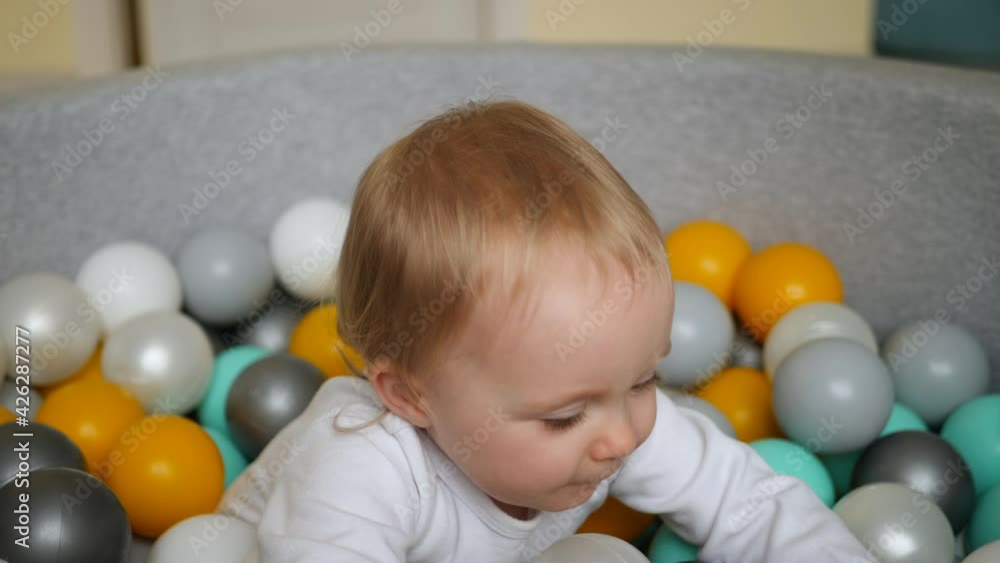 girl in a white bodysuit plays with colorful plastic balls in dry pool girl in a white bodysuit plays with colorful plastic balls in dry pool