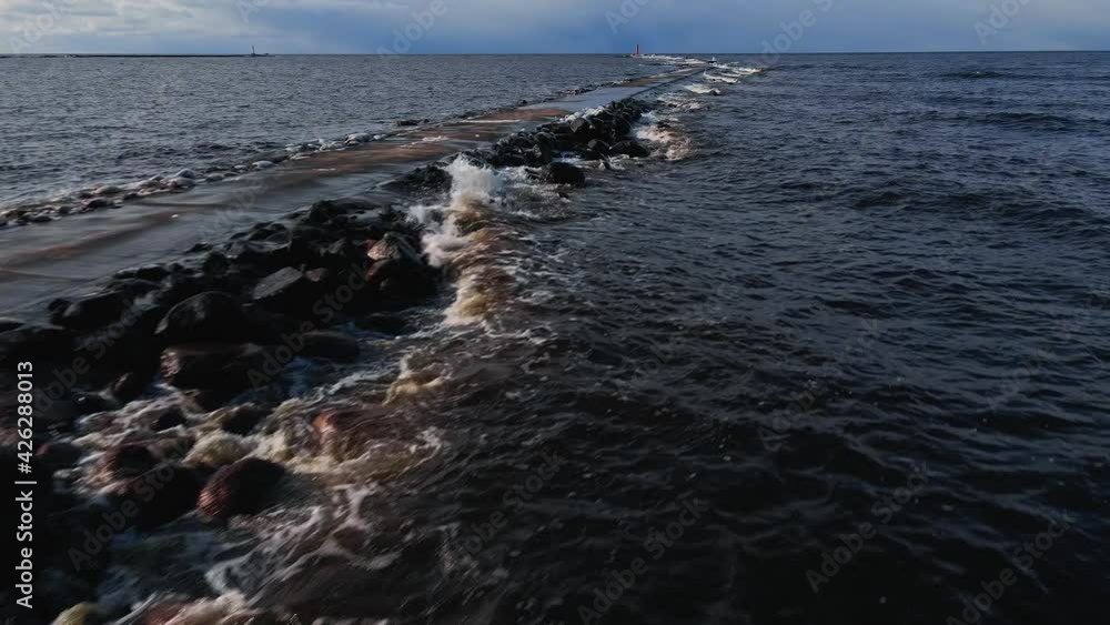 Aerial forward flight: Waves hitting pier and lighthouse in winter with snow and waves Aerial forward flight: Waves hitting pier and lighthouse in winter with snow and waves