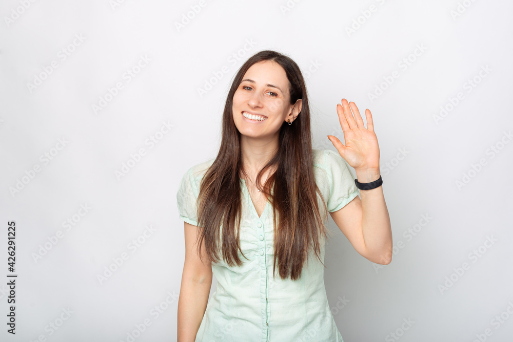Cheerful young smiling woman over white background saying HELLO and gesturing Cheerful young smiling woman over white background saying HELLO and gesturing