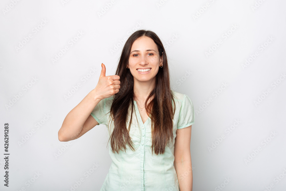 Portrait of smiling young beautiful woman showing thumb up over white background Portrait of smiling young beautiful woman showing thumb up over white background