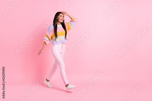 Full length body size view of attractive glad cheerful girl walking searching faw way direction isolated over pink pastel color background
