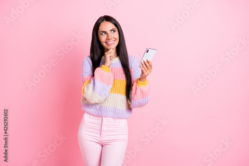 Photo of young cheerful girl happy positive smile think dream look empty space use cellphone isolated over pastel color background