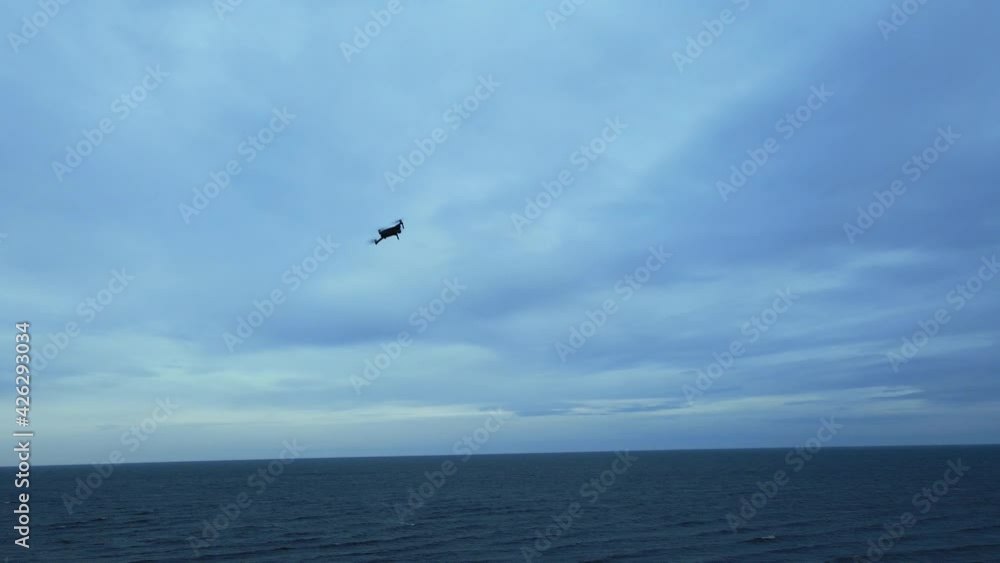 Drone fighting strong wind in air with clouds and sea in background aerial Drone fighting strong wind in air with clouds and sea in background aerial