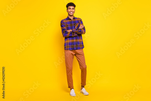 Full length body size photo of young man smiling confident crossed hands isolated vibrant yellow color background