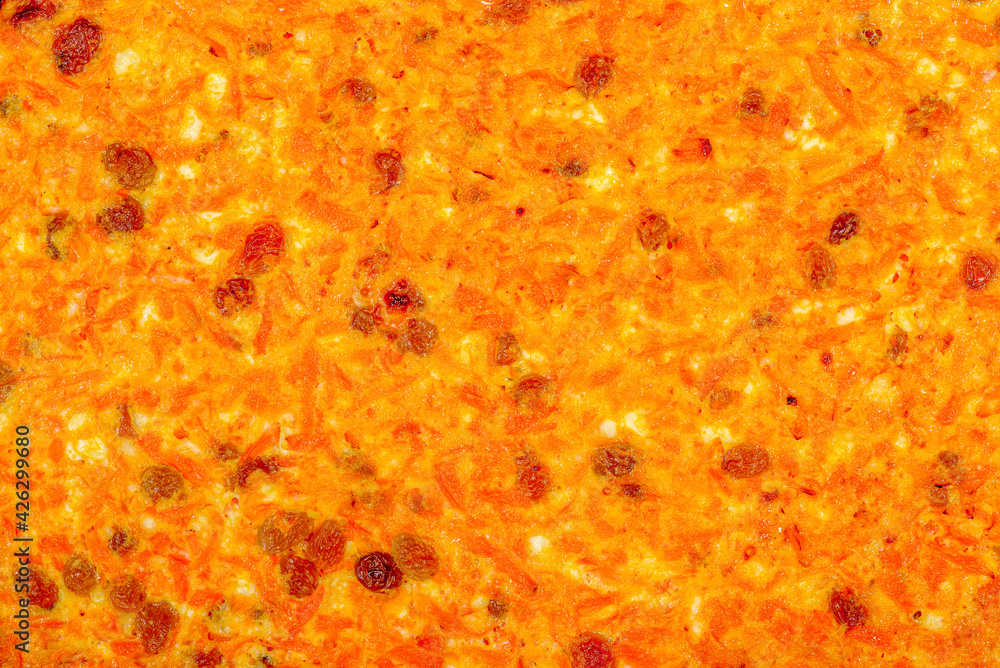 Abstract surface of cottage cheese casserole with raisins, carrots and dried apricots close-up