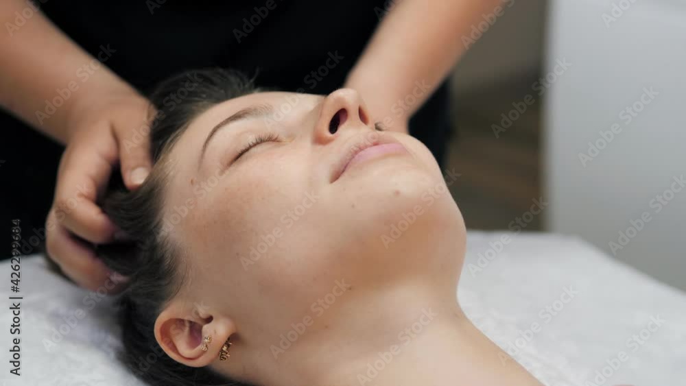Beautiful young girl doing face and head massage in spa salon Beautiful young girl doing face and head massage in spa salon