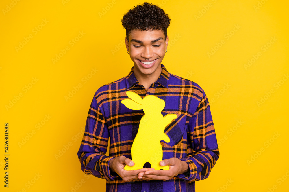 Photo portrait of cheerful man keeping yellow paper hare rabbit on easter holidays smiling isolated on bright yellow color background Photo portrait of cheerful man keeping yellow paper hare rabbit on easter holidays smiling isolated on bright yellow color background