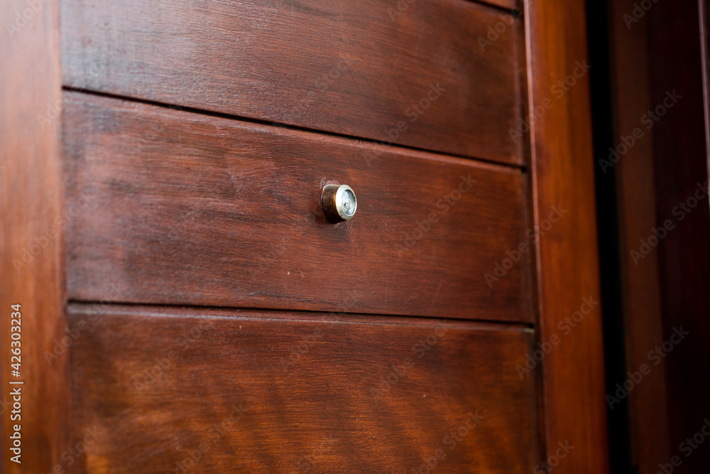 Door lens peephole security on wooden texture