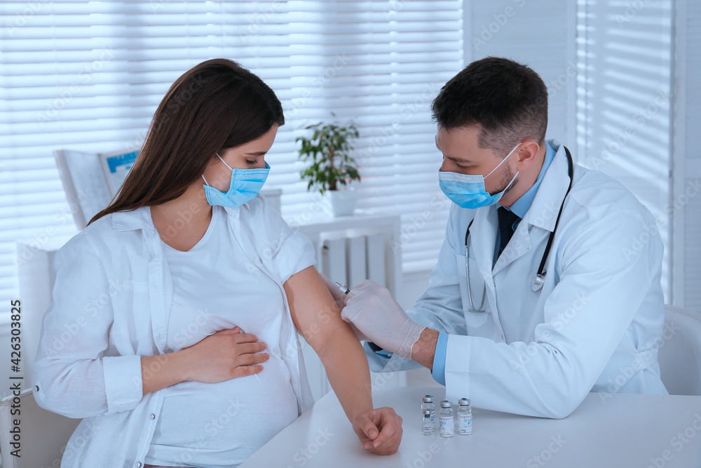 Doctor vaccinating pregnant woman against Covid-19 in clinic Doctor vaccinating pregnant woman against Covid-19 in clinic