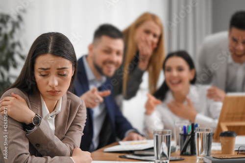 Coworkers bullying their colleague at workplace in office photo