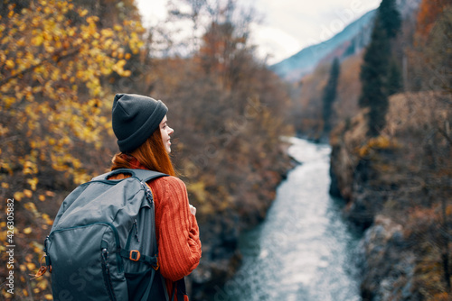 woman hiker with backpack on her back near mountain river in nature