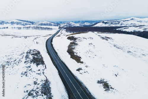 Road in the snow-covered mountains in early spring. Aerial drone view. Beautiful winter landscape. South Ural, Russia photo