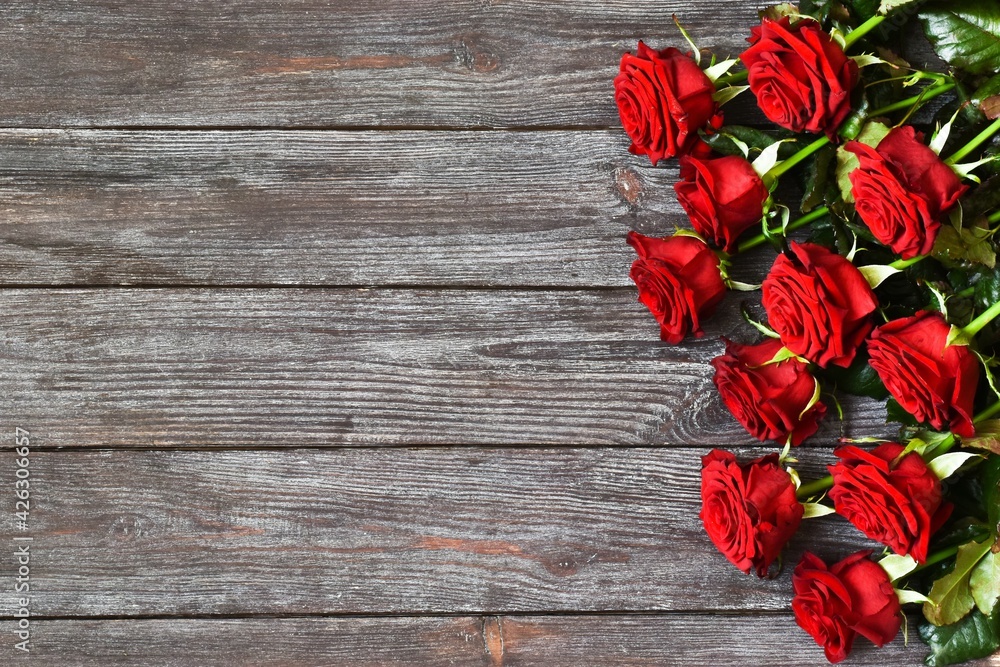Bouquet of red roses on a wooden background. A greeting card. Space for text, top view. Mothers day. Valentines day. Womans day. Happy birhday.