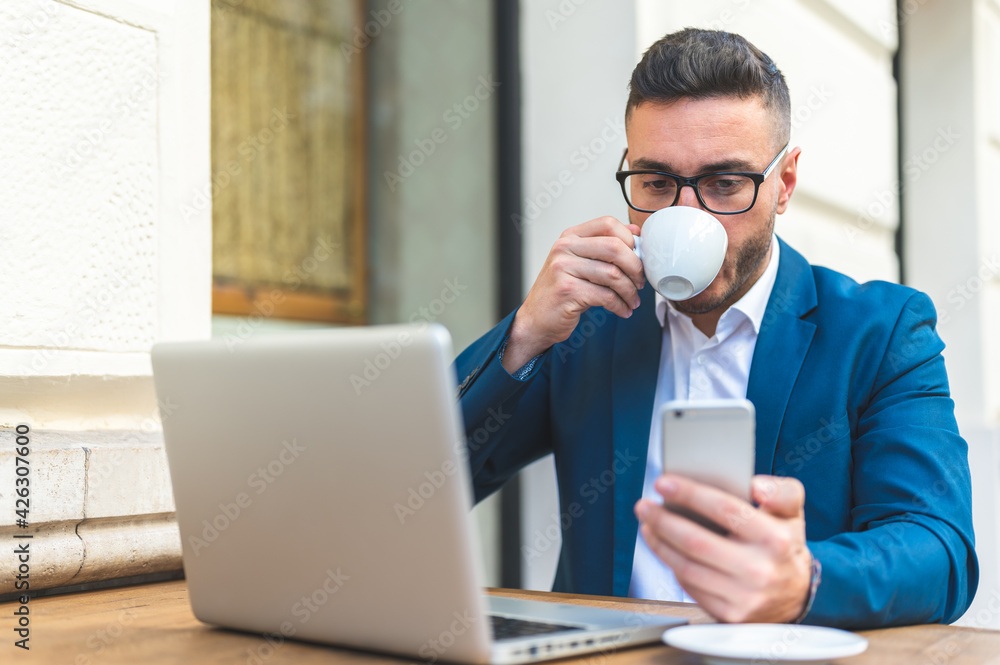 Businessman Using Laptop While Drinking Coffee in a Cafe. Businessman Using Laptop While Drinking Coffee in a Cafe.