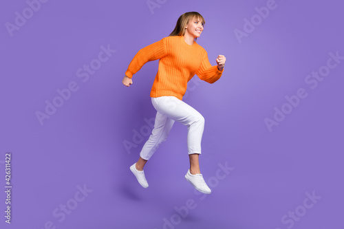 Profile photo of lady jump run fast wear orange sweater trousers footwear isolated violet color background