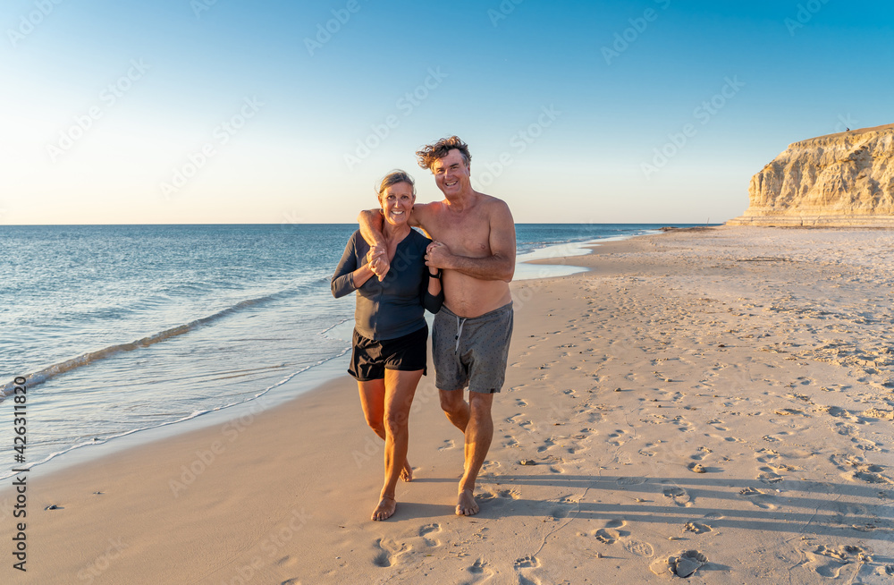Happy active and healthy mature couple walking on the beach enjoying outdoors lifestyle Happy active and healthy mature couple walking on the beach enjoying outdoors lifestyle