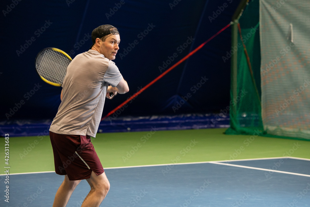 Male tennis player сoncentrated on game. Man waits for the pitch to hit the ball back