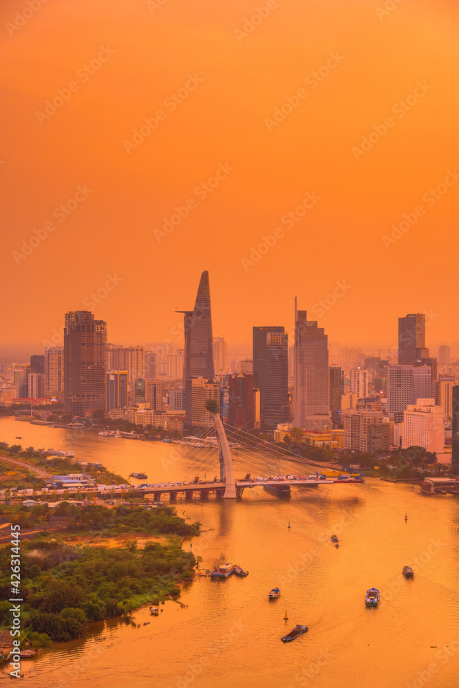 Fototapeta premium Aerial view of Ho Chi Minh city, Vietnam. Beauty skyscrapers along river light smooth down urban development. Dramatic lighting spectacular sunset.