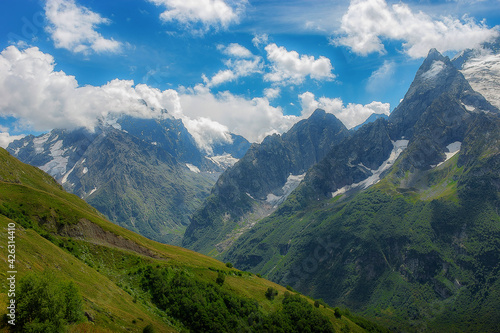 Spring, mountains and peaks covered with green grass and remnants of snow in Dombai, Caucasus