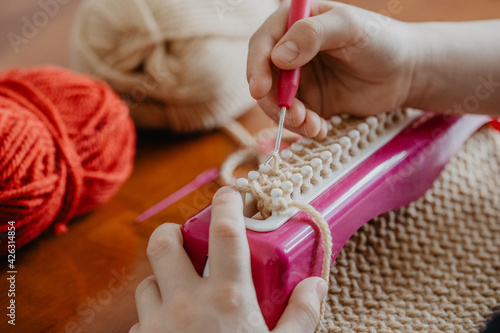 Stricken auf einer Strickbank mit Stricknadel und Wolle  photo