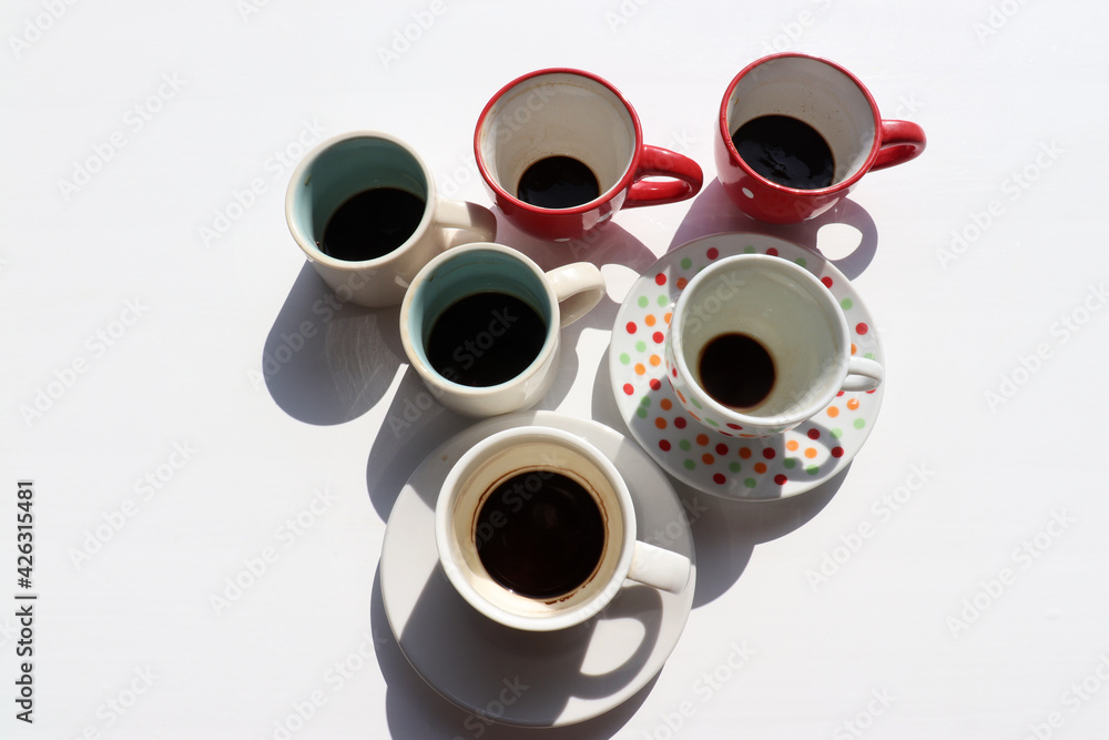 Used dirty coffee cups with coffee grounds on white table background. Hard light, shadow. Summer flat lay minimalist composition. Top view, copy space Used dirty coffee cups with coffee grounds on white table background. Hard light, shadow. Summer flat lay minimalist composition. Top view, copy space