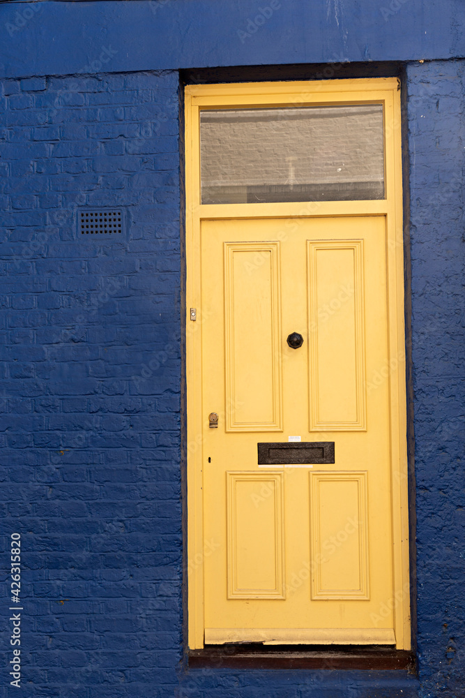 Puerta de madera amarilla y fachada azul.