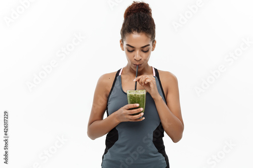 Photo Healthy and Fitness concept - Beautiful American African lady in fitness clothing drinking healthy vegetable drink