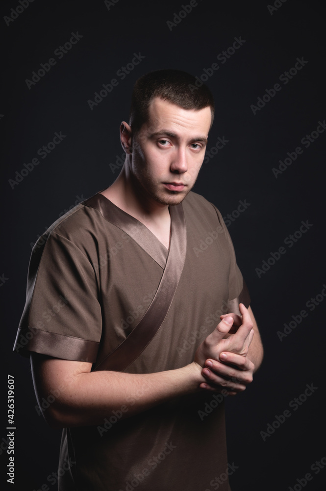 Studio portrait of a young Caucasian massage therapist with an athletic physique. Stretches his hands looking at the camera