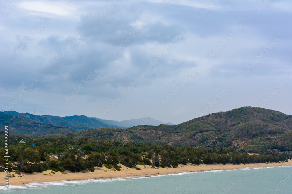 Cloudy day, sand deserted beach of the coast in South China Sea. Sanya, island Hainan, China. Nature Landscape.