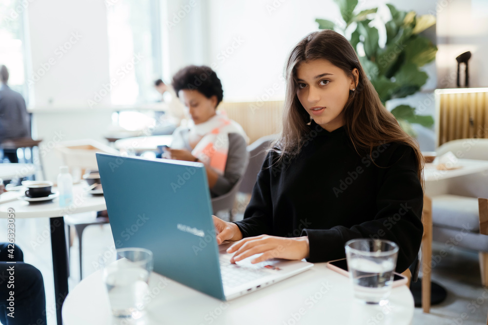 Fototapeta premium Portrait of female student using net-book while sitting in cafe