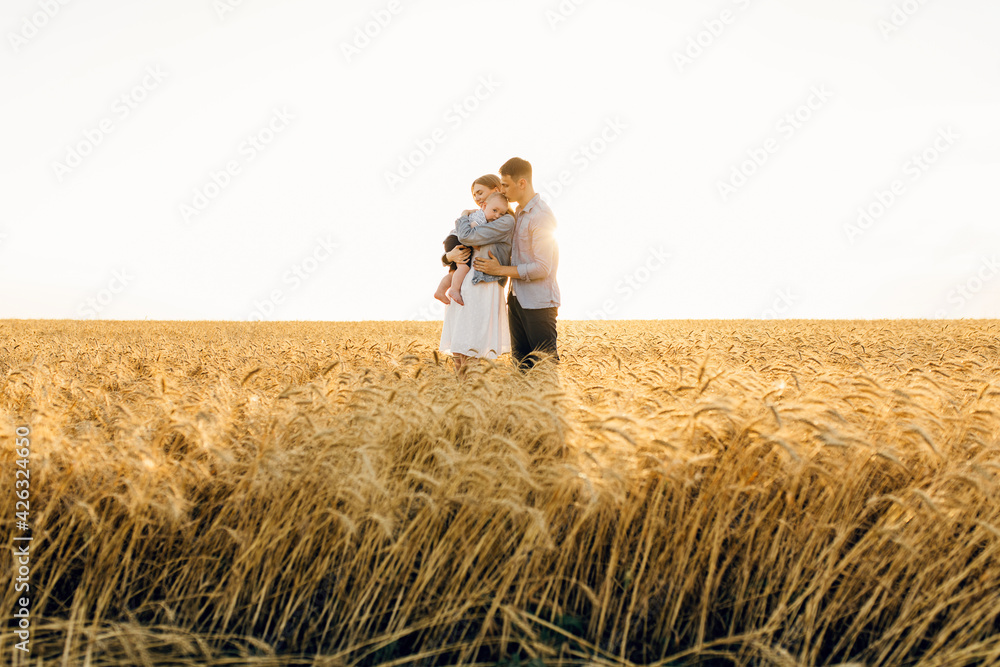 Happy family on a summer walk, mother, father and child walk in the wheat Happy family on a summer walk, mother, father and child walk in the wheat