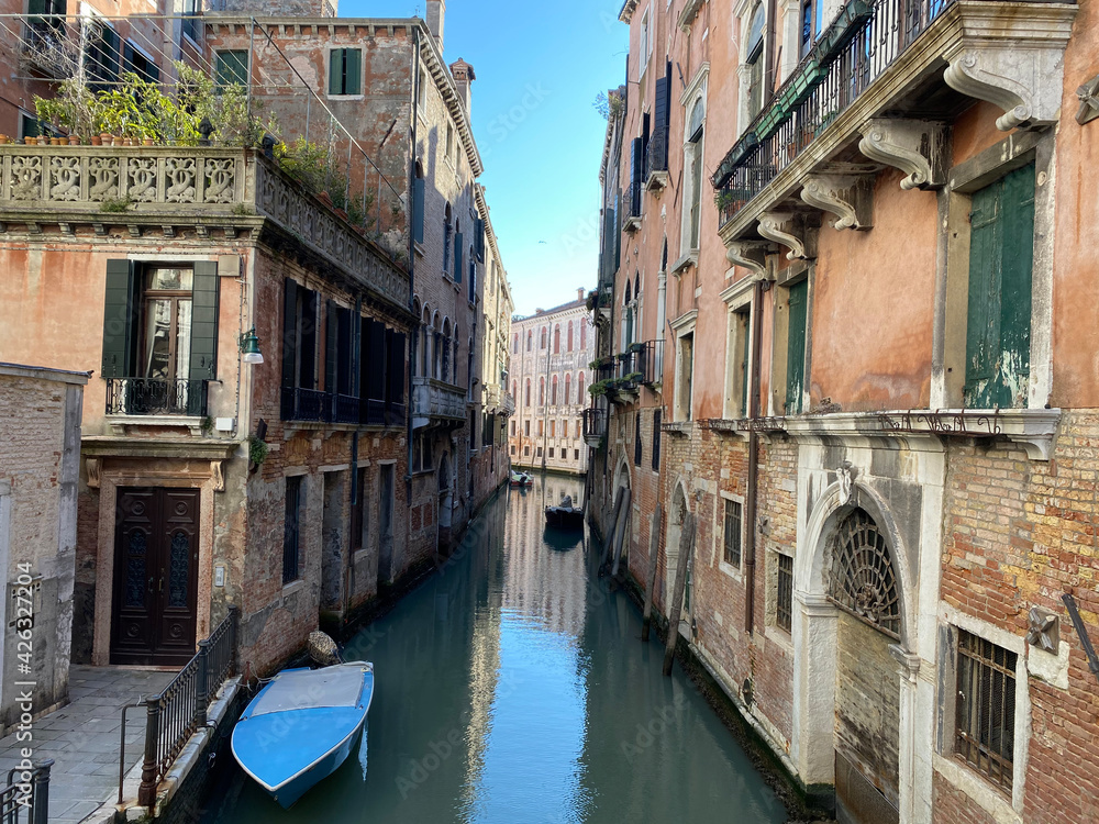 Small boat on a small canal street in Venice with beautiful colorful houses, Italy Small boat on a small canal street in Venice with beautiful colorful houses, Italy