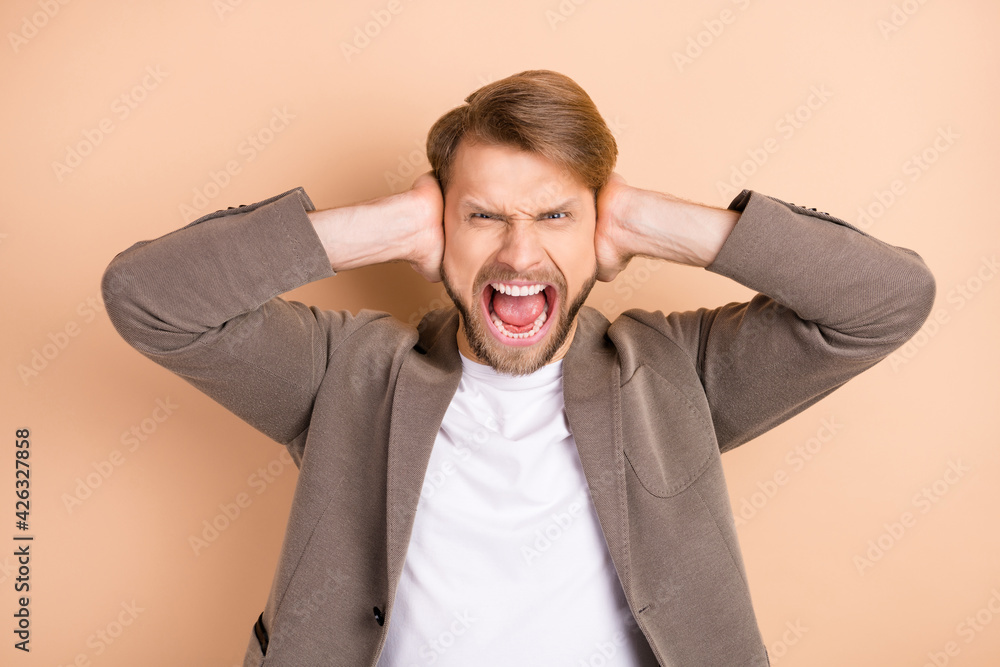 Photo of upset irritated young gentleman dressed blazer screaming arms close ears isolated beige color background