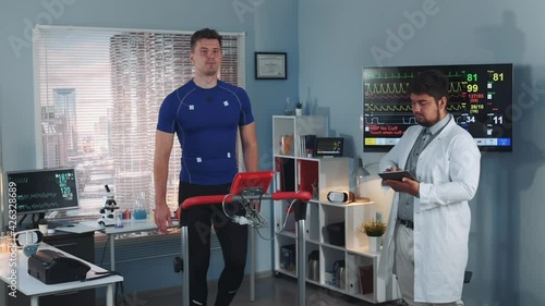 Multiracial sport professional performing stress test while the athlete walking on treadmill