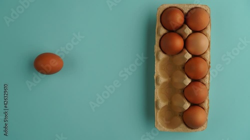 Eggs appear and disappear from cardboard box for eggs on blue background - Stop motion