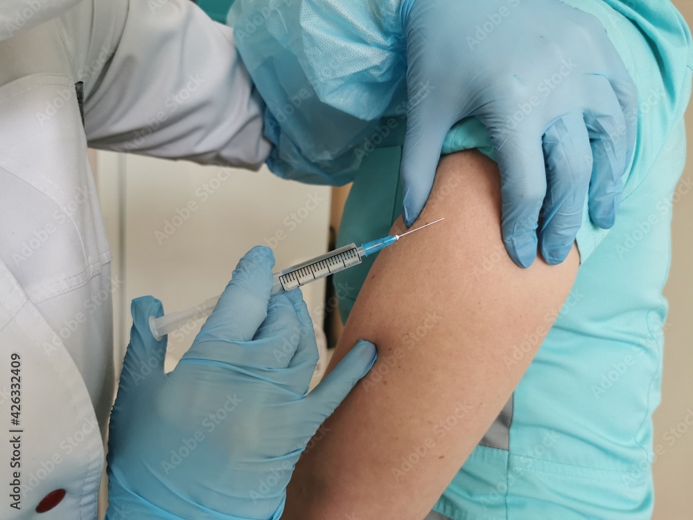 Fototapeta premium A healthcare professional gives an injection into the shoulder. Vaccination against coronavirus, influenza.