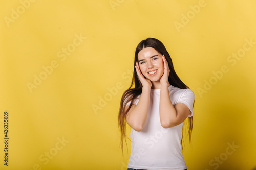 Woman show her nature beauty. Portrait of female in white t-shirt stand in front of yellow background. Pretty girl without makeup