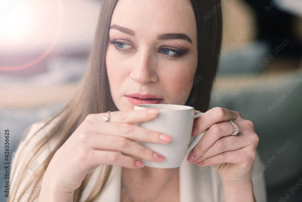 Young woman in white jacket working in cafe with papers, drinking coffee Young woman in white jacket working in cafe with papers, drinking coffee