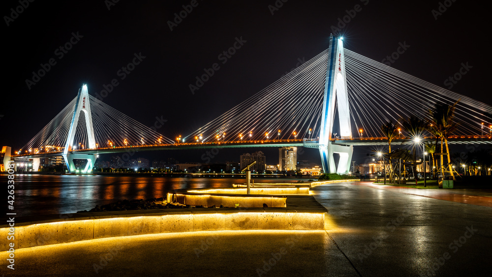 Fototapeta premium Beautiful scenic view of the century bridge with illuminated promenade at night along the Haikou landmark coastline in Haikou Hainan China