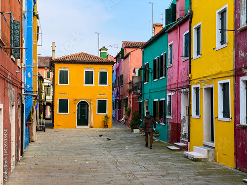 Unrecognizable person walking in the typical and very colorful streets of Burano. We see laundry being dried outside