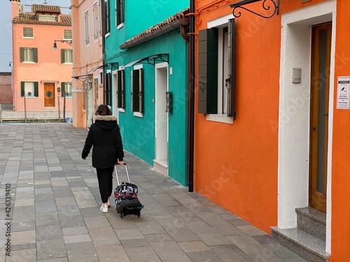 People walking away in a multicolored street at Burano island  Venice  Italy