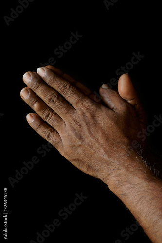 Praying hands of Indian Catholic man isolated on a black background. (ID: 426345248)