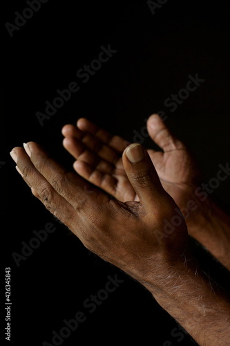 Praying hands of Indian Catholic man isolated on a black background. (ID: 426345843)