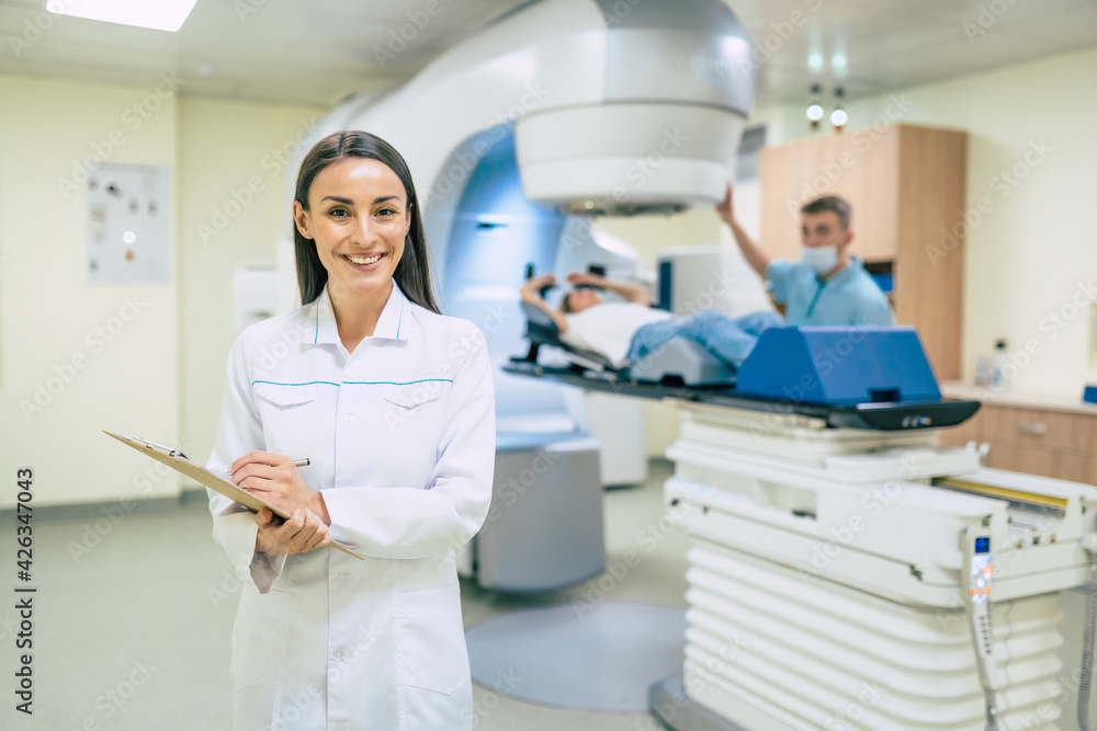 Cancer treatment in a modern medical private clinic or hospital with a linear accelerator. Professional doctors team working while the woman is undergoing radiation therapy for cancer Cancer treatment in a modern medical private clinic or hospital with a linear accelerator. Professional doctors team working while the woman is undergoing radiation therapy for cancer