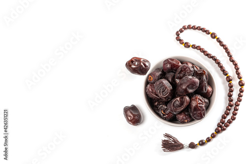 Muslim background for the holy month of Ramadan with dried dates in white bowl, and a rosary on white
