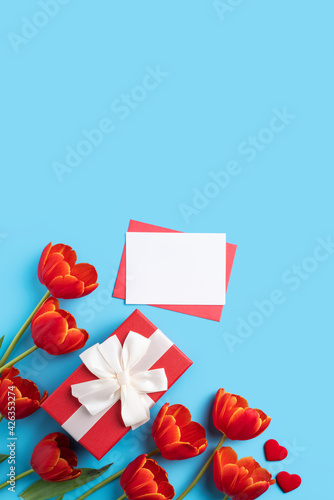 Design concept of Mother's day holiday greeting gift with red tulip bouquet on bright blue table background