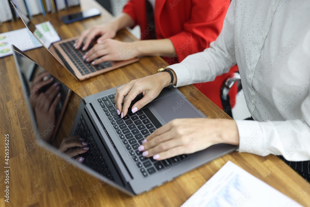 Women typing on laptop keyboard in office closeup Women typing on laptop keyboard in office closeup