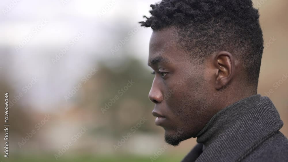 Thoughtful African black man standing outside at park thinking Thoughtful African black man standing outside at park thinking